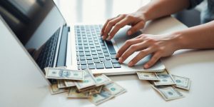 Person using laptop with money around
